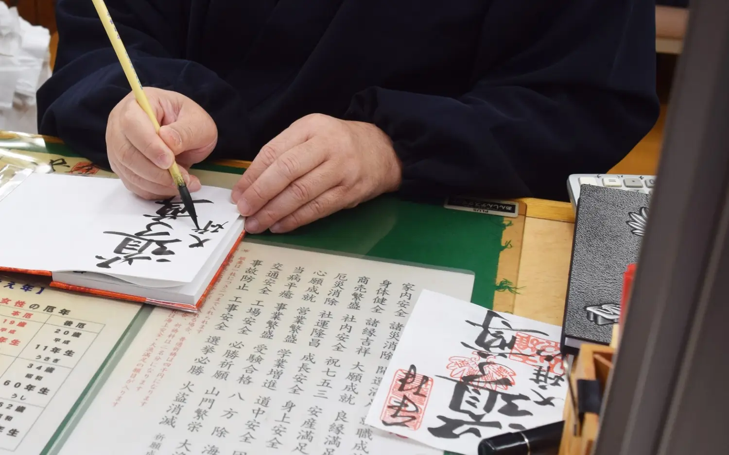 A goshuin being written with a brush in a goshuincho